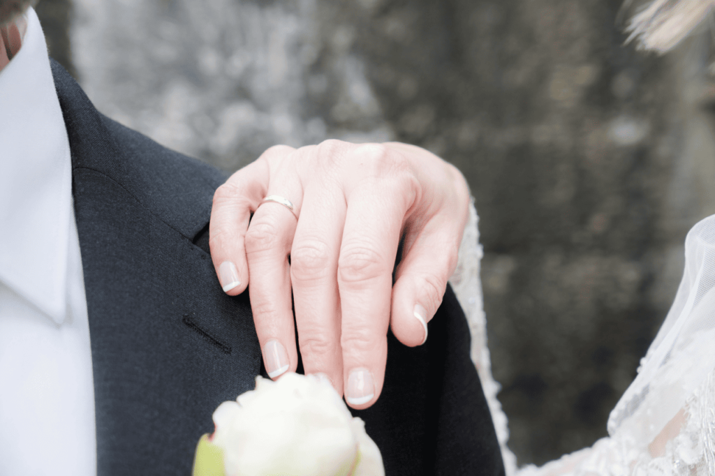 Mão de uma esposa cristã sobre o ombro do marido, simbolizando o compromisso no casamento segundo o ensinamento de Jesus — O Crente e a Bíblia