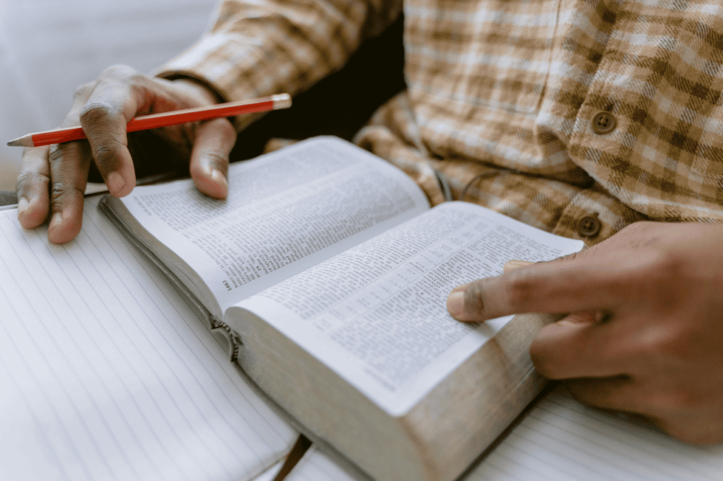 jovem estudando a Bíblia com lápis e caderno, refletindo sobre qual Bíblia comprar